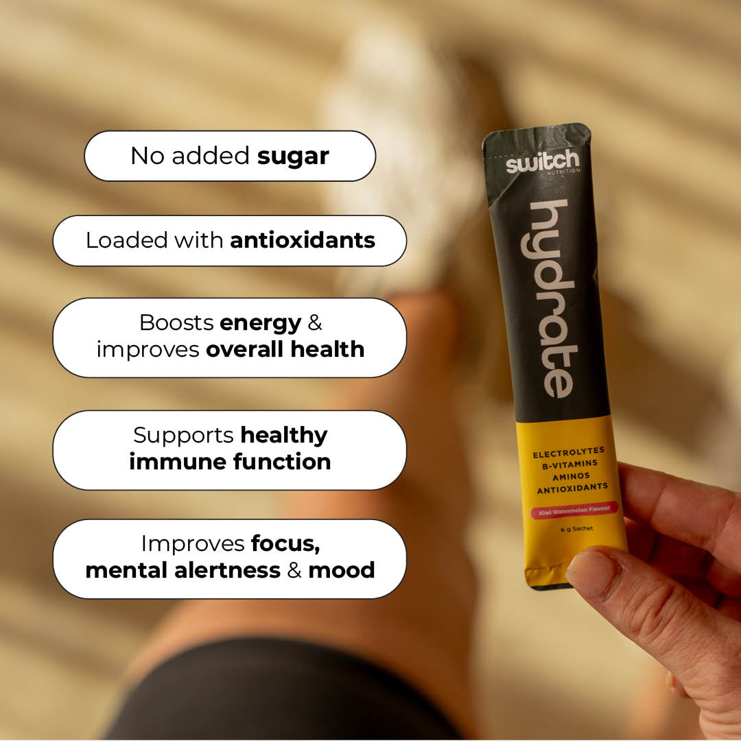 Hand holding a Hydrate sachet with benefits listed: no added sugar, antioxidants, boosts energy and health, supports immune function, and improves focus and mood.