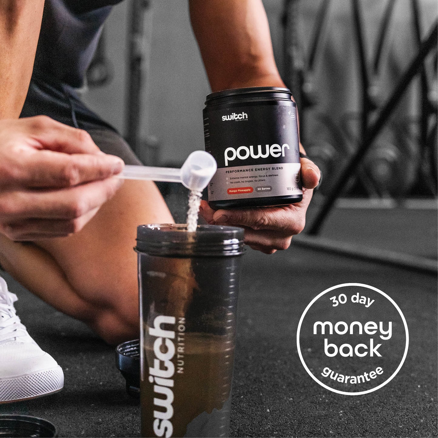 A person kneeling on a gym floor, pouring a scoop of Switch Nutrition Power Performance Energy Blend supplement into a Switch Nutrition shaker bottle. The image includes a "30 day money back guarantee" badge.