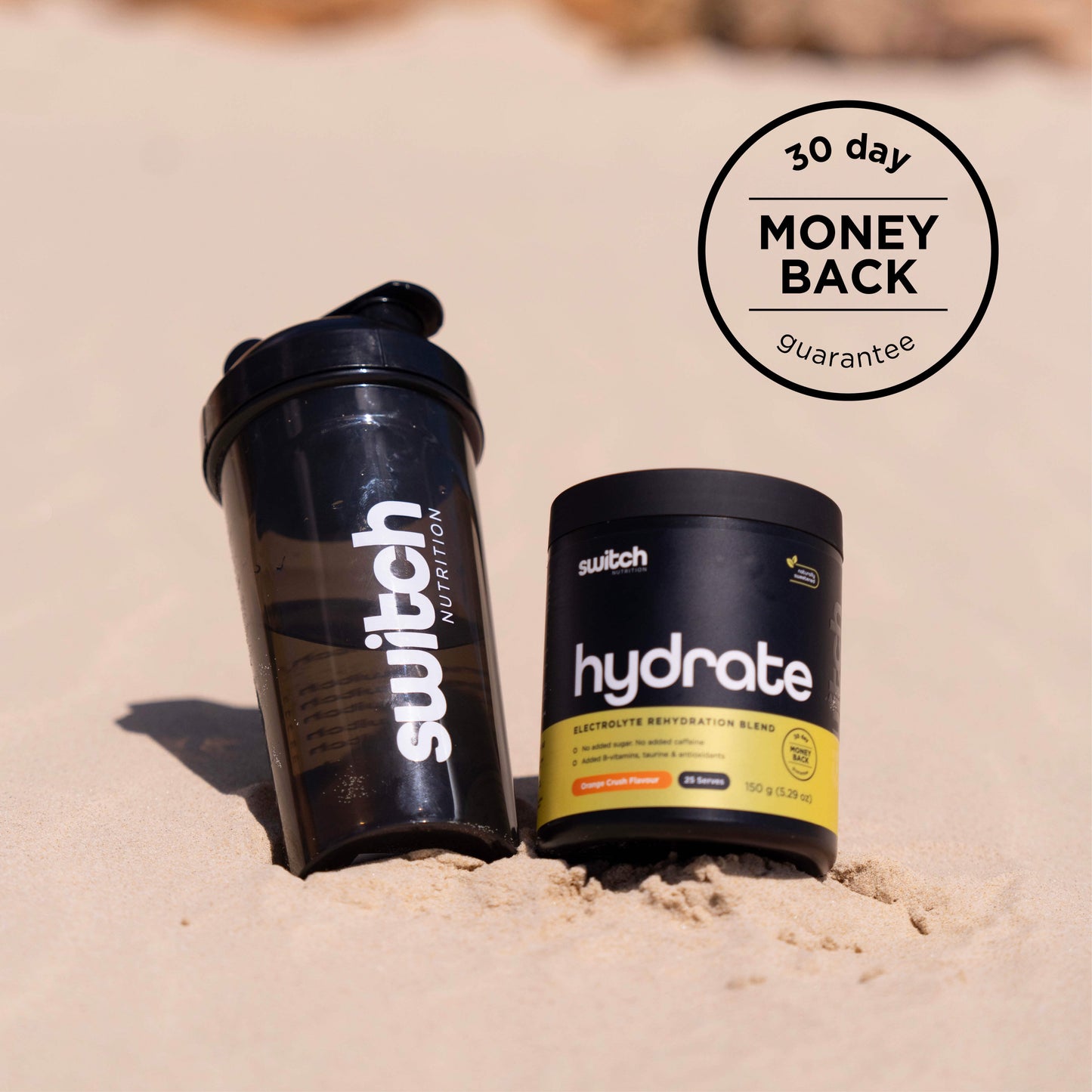 Switch Nutrition Hydrate container next to a water bottle on sandy beach, with a '30 day money-back guarantee' seal.